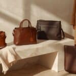 brown handbags under $100: Four brown handbag styles arranged in a neutral fall fashion setting